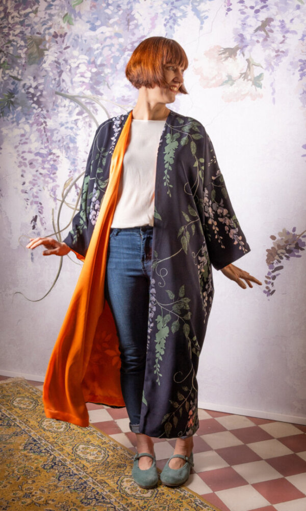 Vintagetyylinen tummansininen evening coat kukkakuosilla Strange Magic verkkokaupasta, yhdistää klassisen eleganssin ja ainutlaatuisen designin. Takissa on oranssi kontrastivuori ja vyö